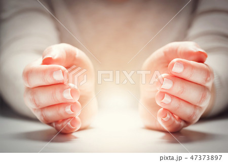 Light between woman's hands in gesture of protection, care. Light between woman's hands in gesture of protection, care. 47373897