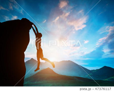 Man hanging on the edge of mountain at sunset 47376117