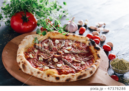 Pizza with anchois and garlic on wooden board. 47376286