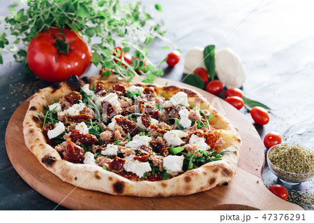 Pizza with dried tomatoes, mozzarella, sausage and rocket 47376291