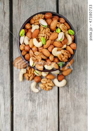 Wooden bowl with mixed nuts on a wooden gray Wooden bowl with mixed nuts on a wooden gray 47380733