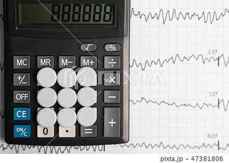 Tablets are on the calculator on background of electrocardiogram 47381806