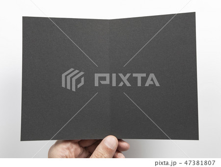 Mens hand holding black booklet 47381807