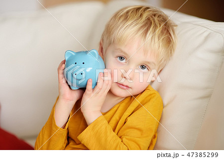 Little boy shaking a piggy moneybox and dreams Little boy shaking a piggy moneybox and dreams 47385299