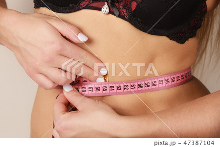 Woman measuring her waist closeup 47387104