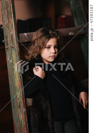 Little girl stand by the ladder in the library. Books 47393187