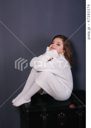 Little beautiful girl with brown hair in a white sweater. Studio. A princess poses for a 47393374