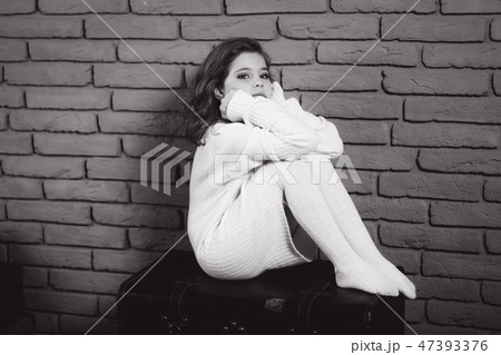 Little beautiful girl with brown hair in a white sweater. Studio. A princess poses for a Little beautiful girl with brown hair in a white sweater. Studio. A princess poses for a 47393376