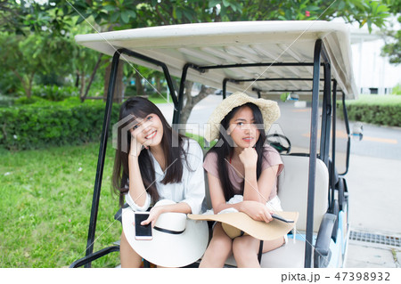 two young asian women sitting on golf cart 47398932