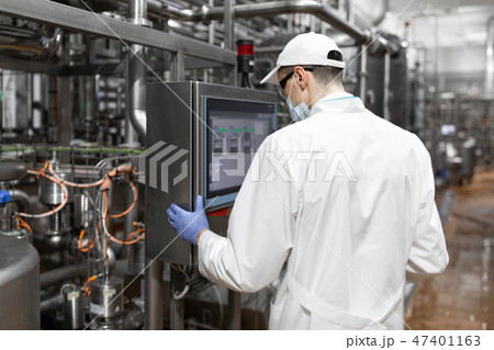 technologist taking necessary notes while standing at production department of dairy factory 47401163