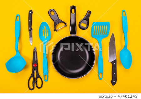 Frying pan with kitchen utensils isolated on yellow background 47401245