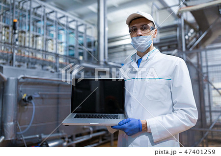 man in a white robe and a mask with a laptop in his hands is at the factory 47401259