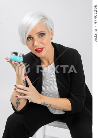 Portrait of confident lady in a suit with a jar of cream in her hands isolated on a light background 47401266
