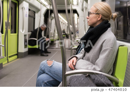 Beautiful blond woman wearing winter coat and scarf traveling by metro. Public transport. Beautiful blond woman wearing winter coat and scarf traveling by metro. Public transport. 47404010