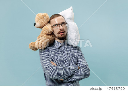 Tired man sleeping at home having too much work. Bored businessman with pillow and toy bear Tired man sleeping at home having too much work. Bored businessman with pillow and toy bear 47413790