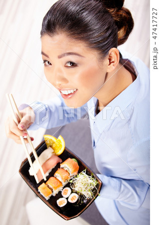Beautiful young woman eating sushi. Shallow depth of field, focu Beautiful young woman eating sushi. Shallow depth of field, focu 47417727