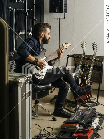 Playing his electric guitar in the recording studio 47418733
