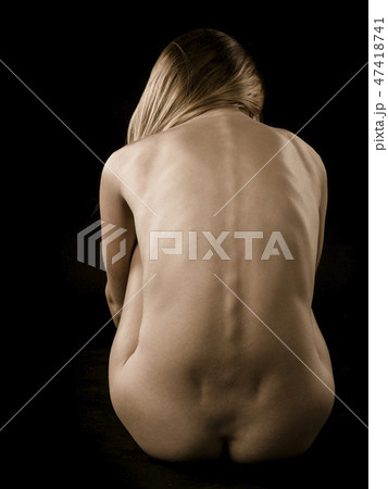 Back of a nude woman over dark background 47418741