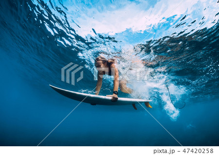 Surfer girl with surfboard dive underwater 47420258
