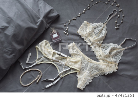 Set of glamorous stylish sexy lace lingerie with woman accessories on grey bedsheets background Set of glamorous stylish sexy lace lingerie with woman accessories on grey bedsheets background 47421251
