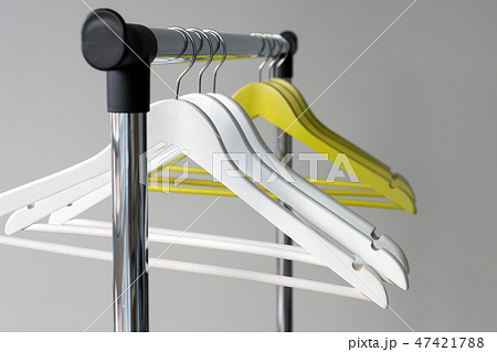 Empty clothes hangers on metal rail against grey background. Rectangular metal clothing rail with Empty clothes hangers on metal rail against grey background. Rectangular metal clothing rail with 47421788