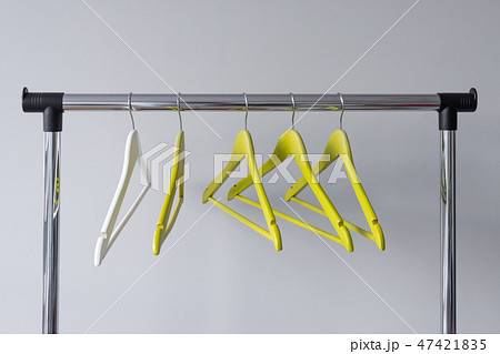 Empty clothes hangers on metal rail against grey background. Rectangular metal clothing rail with 47421835