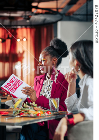 African-American woman wearing bright accessories reading book 47422079