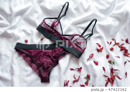 Set of glamorous stylish sexy lace lingerie with flowers on white bedsheets background. Woman Set of glamorous stylish sexy lace lingerie with flowers on white bedsheets background. Woman 47422162