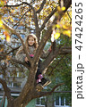 A pretty girl sitting on a tree near the building 47424265