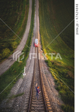 Aerial view A male hipster in a cap holding up a hand with a gesture Victory is standing on rails in 47424848