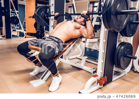 Muscular bodybuilder bench press workout in modern gym 47426069