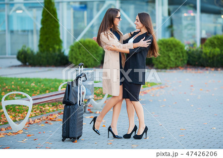 Female Friends Have a Trip Together. Front View of Cute Brunettes with Luggage at the Airport 47426206