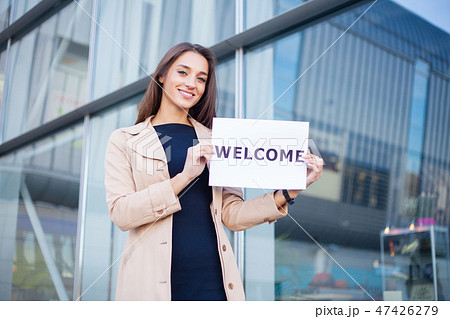 Businesswoman with long Hair Holding a sign Board with a Welcome has Airport Background 47426279