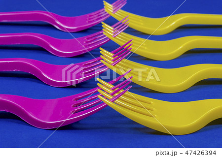 Colorful purple and yellow plastic forks on blue Colorful purple and yellow plastic forks on blue 47426394