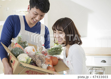 キッチンで届いた野菜を妻に見せる夫 47433603