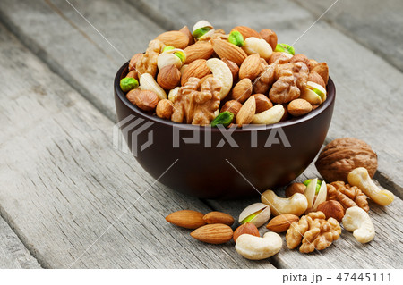 Wooden bowl with mixed nuts on a wooden gray  47445111