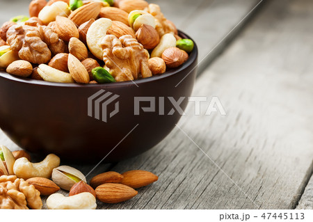 Wooden bowl with mixed nuts on a wooden gray Wooden bowl with mixed nuts on a wooden gray 47445113