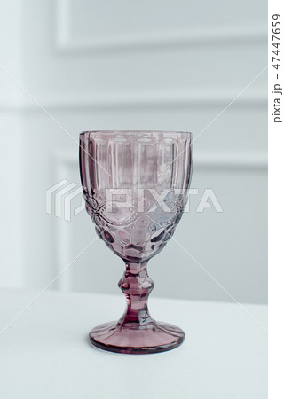 Embossed colored drink glasses for wine on a white wooden table. 47447659