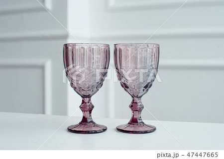 Embossed colored drink glasses for wine on a white wooden table. Embossed colored drink glasses for wine on a white wooden table. 47447665