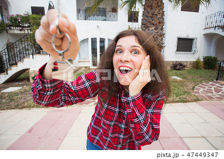 Ownership, real estate, purchase and rent concept - Woman with keys standing outside new home 47449347