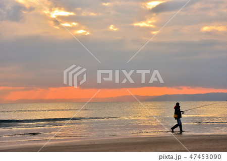 夕焼けに染まる材木座で釣りをする人 47453090