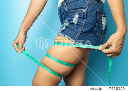 woman is measuring her thigh with measuring tape  47456390