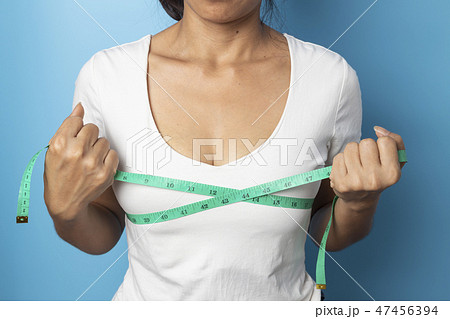 woman measuring her bust size with green measu 47456394