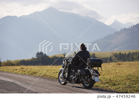 Biker in black leather outfit driving modern powerful motorcycle along sunny road on summer day. Biker in black leather outfit driving modern powerful motorcycle along sunny road on summer day. 47459246