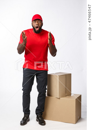 Delivery Concept: Handsome african delivery man shocking facial expression. Isolated over grey Delivery Concept: Handsome african delivery man shocking facial expression. Isolated over grey 47466547