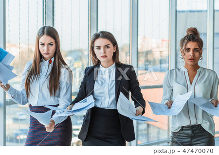 Three young beautiful brunette business ladies in the office. All serious, talking with each other Three young beautiful brunette business ladies in the office. All serious, talking with each other 47470070