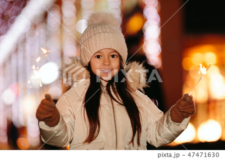 Cute smiling little girl with bengal lights on the street in the evening Cute smiling little girl with bengal lights on the street in the evening 47471630