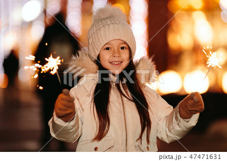 Cute smiling little girl with bengal lights on the street in the evening Cute smiling little girl with bengal lights on the street in the evening 47471631