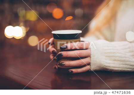 female hands holding a paper cup with hot coffee 47471636