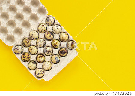 Quail eggs in cardboard box on yellow background 47472929